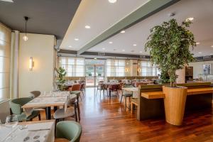 a restaurant with tables and chairs and a plant at Tulip Inn Turin West Rivoli in Rivoli