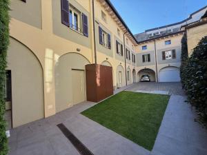 an empty courtyard with a lawn in front of a building at Malvezzi24 Boutique Rooms in Desenzano del Garda