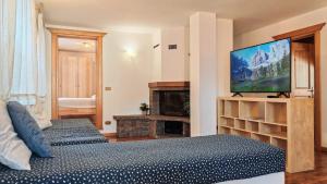 a bedroom with two beds and a flat screen tv at Tabia del Caser in San Tomaso