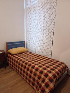 a small bedroom with a bed with a plaid blanket at Da Lucia in Dronero