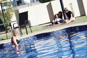 a woman sitting in the swimming pool with her family at Jacaranda Holiday Units in Swan Hill