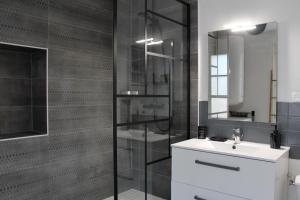 a bathroom with a sink and a glass shower at Le Duplex appartement proche de la Cathédrale in Bayeux
