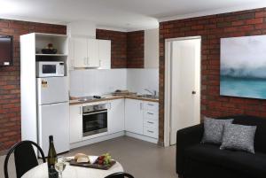 a kitchen with white appliances and a black couch in a room at Jacaranda Holiday Units in Swan Hill