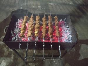 a grill with several skewers of food on it at B&B Villa Maurizio in Tsqaltubo