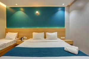 a bedroom with two beds and a green wall at Hotel H One in Pune