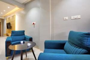 a living room with two blue chairs and a table at Hotel H One in Pune