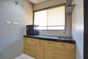 a small kitchen with a sink and a window at Hotel H One in Pune