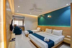a bedroom with two beds and a flat screen tv at Hotel H One in Pune +7 photos