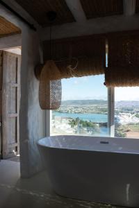 a bath tub in a bathroom with a large window at Laan Arcos, casa cueva in Arcos de la Frontera