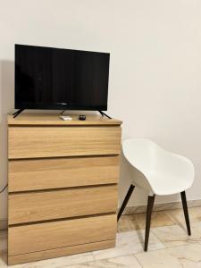a tv sitting on top of a dresser with a white chair at Metis Apartments Bellizzi in Bellizzi