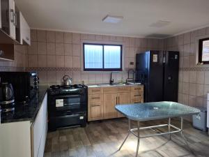 a kitchen with a black refrigerator and a table at Casa para 8 personas in Licán Ray