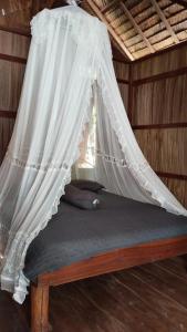a bed with a mosquito net on top of it at Frits Homestay in Kri