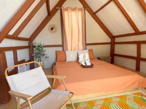 a bedroom with a bed and a chair in a room at Tatak Balabac Beach Camp in Olorga