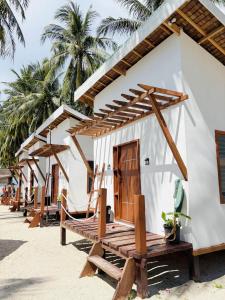 a house on the beach with wooden benches in front at Tatak Balabac Beach Camp in Olorga