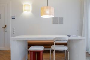 a kitchen with a white counter with two stools at Hotel Montaigne in Ostend