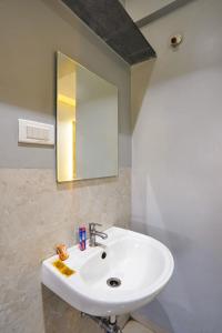 a bathroom with a white sink and a mirror at Hotel H One in Pune