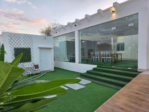 a modern house with a green yard with glass walls at Wadi Bani Khalid - Al Joud Green Hostel in Zilaft