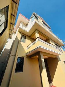a yellow building with a balcony on top of it at Pharping StayInn in Pharping +10 photos