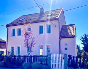 a white house with a fence in front of it at Libás Apartman in Keszthely