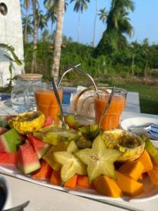 a plate of fruit on a table with drinks at The black monkey villa - Private pool in Kosgoda