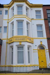 a white building with a yellow door on a street at Sunset Suites in Blackpool