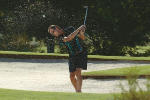 Eine Frau schwingt im Regen einen Golfschläger. in der Unterkunft Murray Downs Resort in Swan Hill