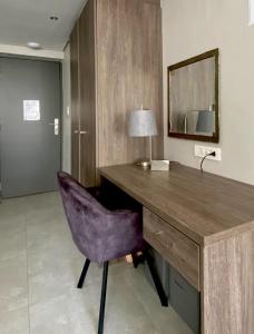 a desk with a purple chair and a mirror at CityNest Hotel Apartment in Cape Town