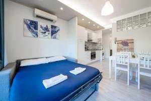 a bedroom with a blue bed and a kitchen at Desenzano - 2' to Station & Lake - Pool, Wifi, AC in Desenzano del Garda