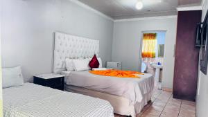 a bedroom with two beds with an orange blanket at Village Boiketlo in Bloemfontein
