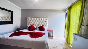 a bedroom with a large bed with red pillows at Village Boiketlo in Bloemfontein