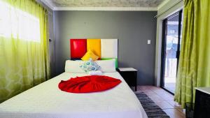 a bedroom with a bed with a red dress on it at Village Boiketlo in Bloemfontein +3 photos