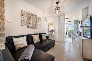a living room with a black couch and a kitchen at Casa Louro in Cabanas de Tavira