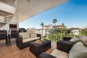 a living room with furniture and a balcony with palm trees at Casa Louro in Cabanas de Tavira