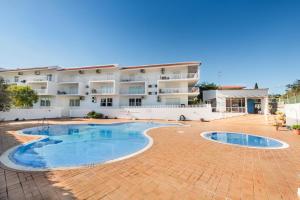 an apartment building with a swimming pool in front of it at Casa Louro in Cabanas de Tavira