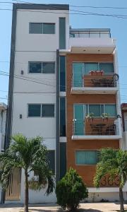 a white building with a balcony with tables and palm trees at Habitaciones amuebladas Veracruz Logos in Veracruz