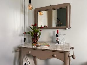 a table with a vase of flowers and a mirror at B&B en theetuin Loodiep in Zwinderen