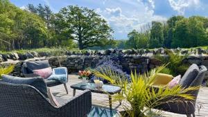 a patio with chairs and a table and a stone wall at Ty Coets in Llanfairpwllgwyngyll