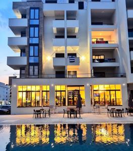 a building with tables and chairs in front of a pool at Cataleya Hotel in Ulcinj