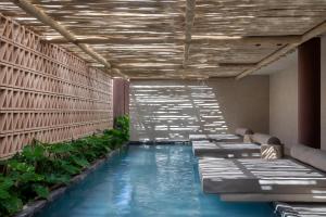 a pool in a room with chairs and plants at Mana Cumbuco Hotel in Cumbuco