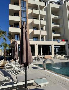 a pool with chairs and umbrellas in front of a building at Cataleya Hotel in Ulcinj