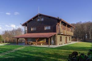 a large wooden house with a deck on a grass field at Pensiunea Casa Brancovenilor in Sâmbăta de Sus