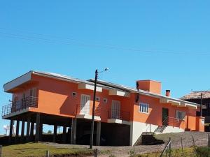 an orange and white building with a fence in front of it at Pousada Aparados in Cambará