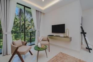 a living room with a tv and chairs and a table at Orbit88 Hotel by AMR in Kandy