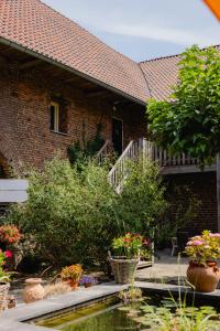 a brick house with potted plants and a pond at Hoeve de Binnenplaets - Appartementen - Glamping - Familieverblijf in Schimmert