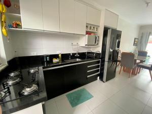 a kitchen with white cabinets and a black counter top at Pool house próximo ao centro in Matinhos