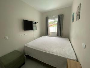 a bedroom with a bed and a flat screen tv at Pool house próximo ao centro in Matinhos
