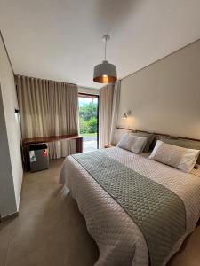 a bedroom with a large bed and a large window at Vila Poção - Hospedagem de Natureza em Brotas in Brotas