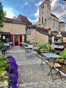 a patio with tables and chairs in front of a castle at Maison Lapopie chambres et gîte in Saint-Cirq-Lapopie