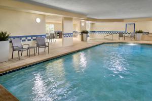 a pool in a hotel room with chairs and tables at Fairfield Inn & Suites Warner Robins in Warner Robins