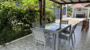 a glass table and chairs on a patio at River Side in Sainte-Rose